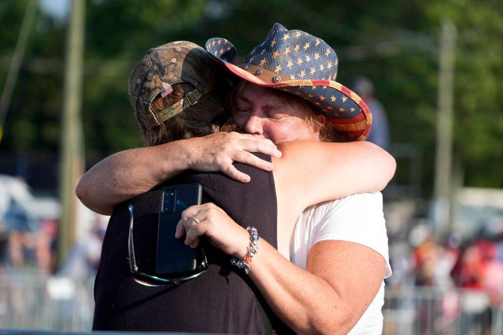 GENE J. PUSKAR / THE ASSOCIATED PRESS
                                People hug after Trump was helped off the stage at a campaign event in Butler, Pa., on Saturday, July 13, 2024.