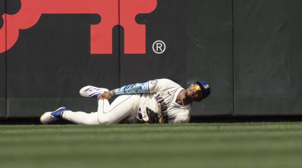 Seattle Mariners centerfielder Julio Rodriguez hold his leg after crashing into the outfield wall while trying to catch the ball during the sixth inning of a baseball game against the Houston Astros, Sunday, July 21, 2024, in Seattle. (AP Photo/Stephen Brashear)