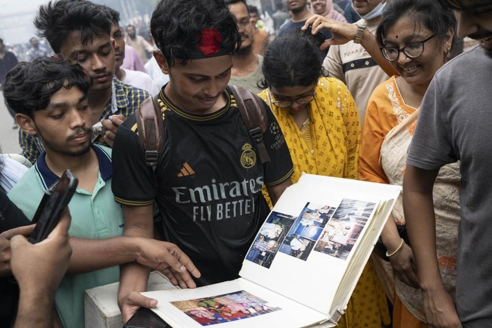 Protesters look through a photo album taken from the house of Prime Minister Sheikh Hasina in Dhaka, Bangladesh, Monday, Aug. 5, 2024. (AP Photo/Fatima Tuj Johora)