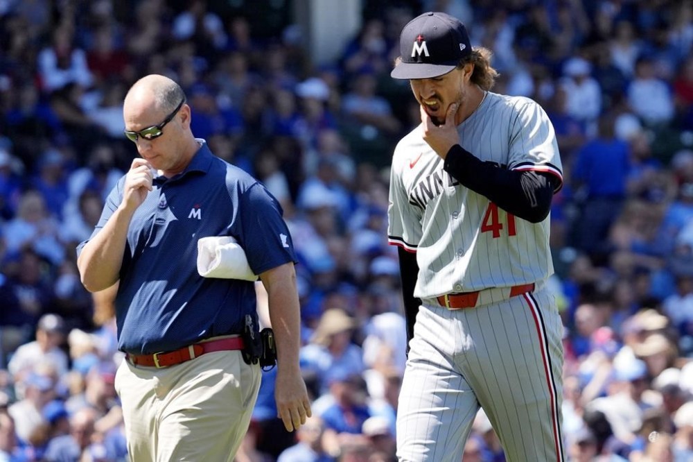 Minnesota Twins starting pitcher Joe Ryan, right, reacts as he leaves with a team trainer after an injury during the third inning of a baseball game against the Chicago Cubs in Chicago, Wednesday, Aug. 7, 2024. (AP Photo/Nam Y. Huh)