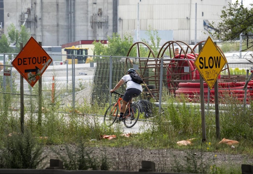 A cyclist negotiates a bike path through the Don River Revitalization and Gardiner Expressway Demolition projects in Toronto on Thursday August 17, 2023. The City of Toronto says it has laid bylaw charges against two companies that illegally left a construction bin on the road where a 24-year-old cyclist died after being struck by a dump truck last month. THE CANADIAN PRESS/Frank Gunn