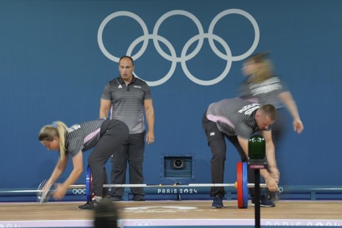 Loaders set the weight on the bar during the women's 59kg weightlifting event at the 2024 Summer Olympics, Thursday, Aug. 8, 2024, in Paris, France. (AP Photo/Kin Cheung)