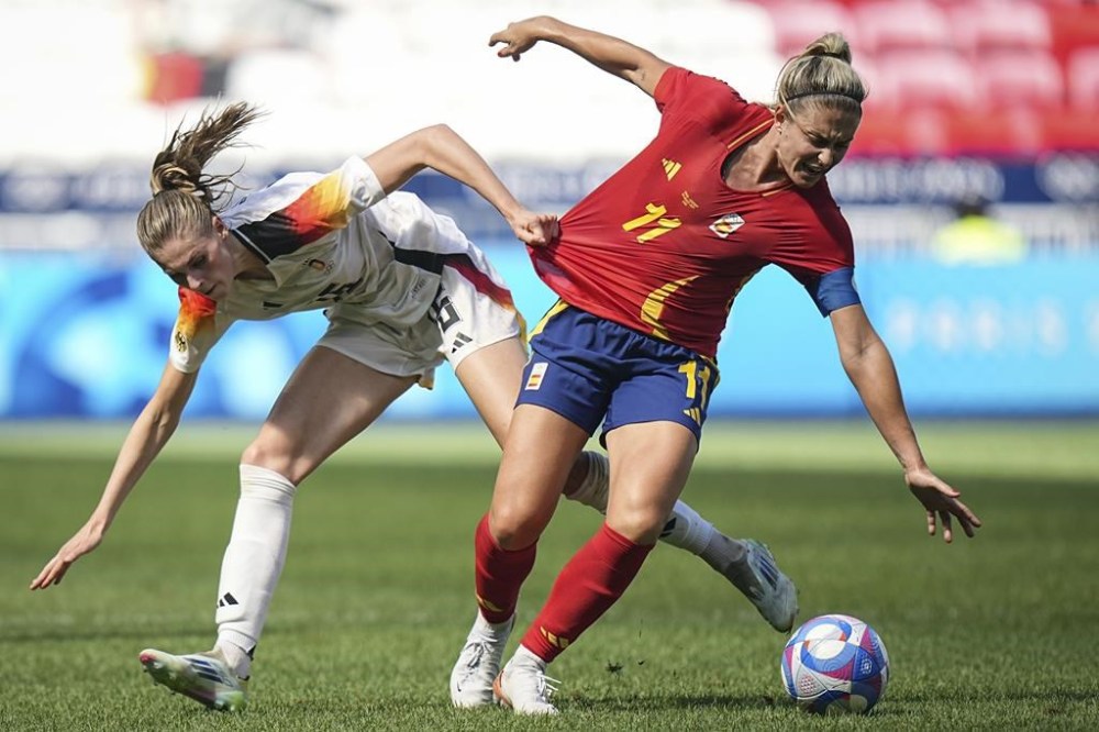 Spain's Alexia Putellas, right, challenges for the ball with Germany's Jule Brand, left, during the women's bronze medal soccer match between Spain and Germany, at the Lyon stadium, during the 2024 Summer Olympics, Friday, Aug. 9, 2024, in Decines, France. (AP Photo/Laurent Cipriani)
