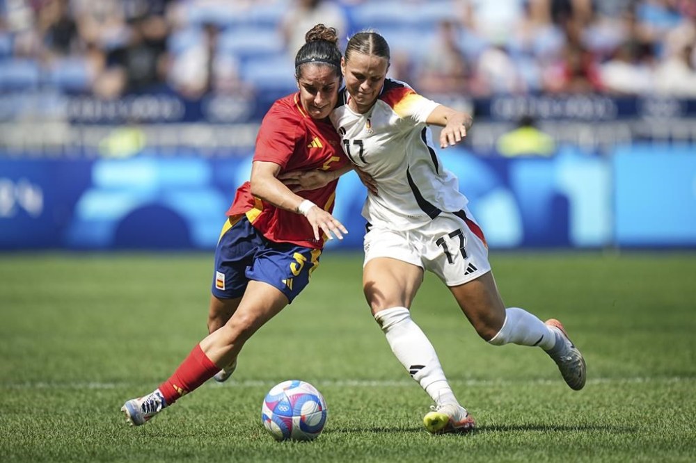 Spain's Oihane Hernandez, left, challenges for the ball with Germany's Klara Buehl, right, during the women's bronze medal soccer match between Spain and Germany, at the Lyon stadium, during the 2024 Summer Olympics, Friday, Aug. 9, 2024, in Decines, France. (AP Photo/Laurent Cipriani)