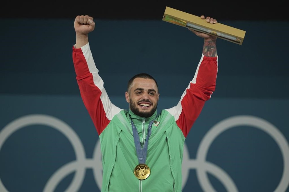Gold medalist Karlos May Nasar of Bulgaria celebrates on the podium during the medal ceremony for the men's 89kg weightlifting event at the 2024 Summer Olympics, Friday, Aug. 9, 2024, in Paris, France. (AP Photo/Kin Cheung)