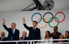 France's President Emmanuel Macron, center, and IOC President Thomas Bach, left, wave as they arrive to attend the opening ceremony for the 2024 Summer Olympics in Paris, France, Friday, July 26, 2024. (Loic Venance/Pool Photo via AP)