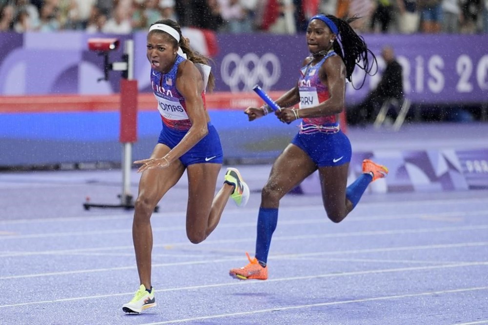 Gabrielle Thomas, left, of the United States, reaches for the baton from teammate Twanisha Terry, for her leg of the women's 4x100-meter relay final at the 2024 Summer Olympics, Friday, Aug. 9, 2024, in Saint-Denis, France. (AP Photo/Matthias Schrader)