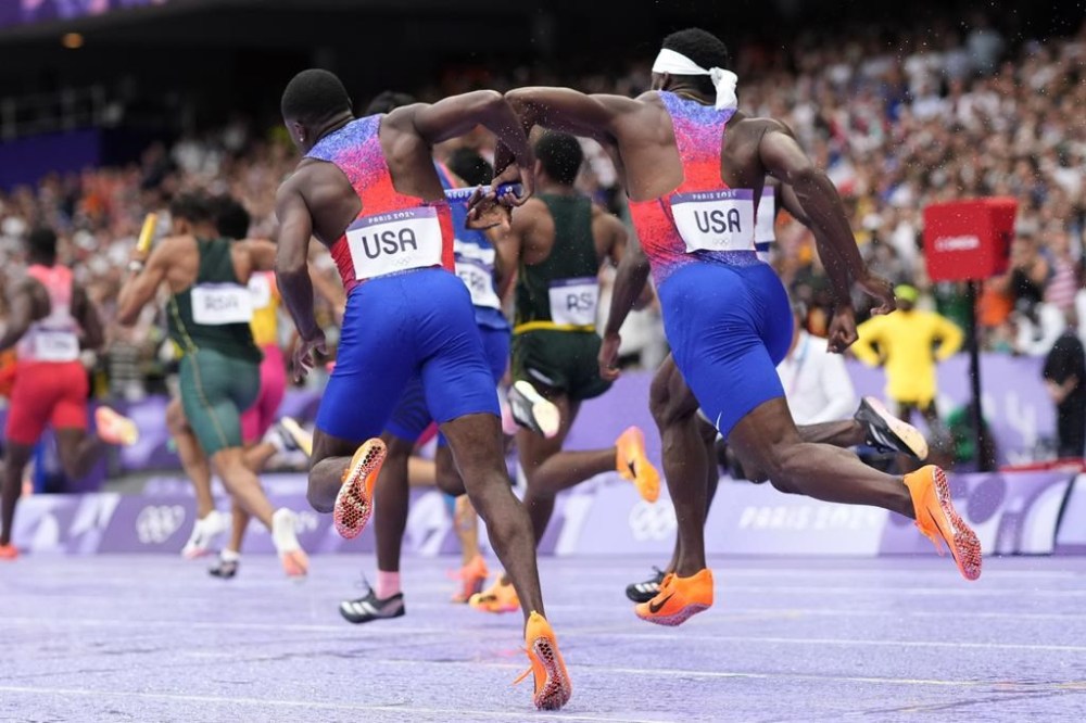 Christian Coleman, left, of the United States, struggles to hand the baton to teammate Kenneth Bednarek, in the men's 4x100-meter relay final at the 2024 Summer Olympics, Friday, Aug. 9, 2024, in Saint-Denis, France. (AP Photo/Bernat Armangue)
