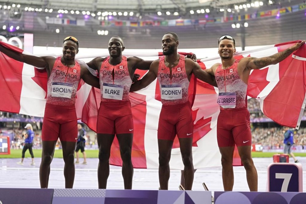 Team Canada pose after winning the gold medal in the men's 4 x 100 meters relay final at the 2024 Summer Olympics, Friday, Aug. 9, 2024, in Saint-Denis, France. (AP Photo/Ashley Landis)
