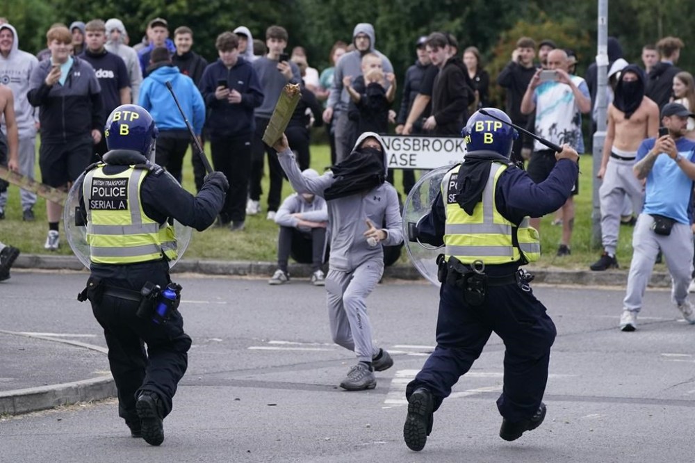 A youth throws a fence post towards police during an anti-immigration demonstration near the Holiday Inn Express hotel in Rotherham, South Yorkshire, England, on Sunday, Aug. 4, 2024. (Danny Lawson/PA via AP)