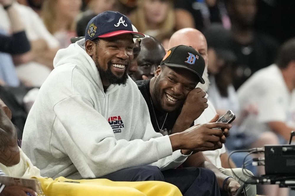 Kevin Durant smiles while watching the USA vs' Australia match up during a women's semifinal basketball game at Bercy Arena at the 2024 Summer Olympics, Friday, Aug. 9, 2024, in Paris, France. (AP Photo/Michael Conroy)
