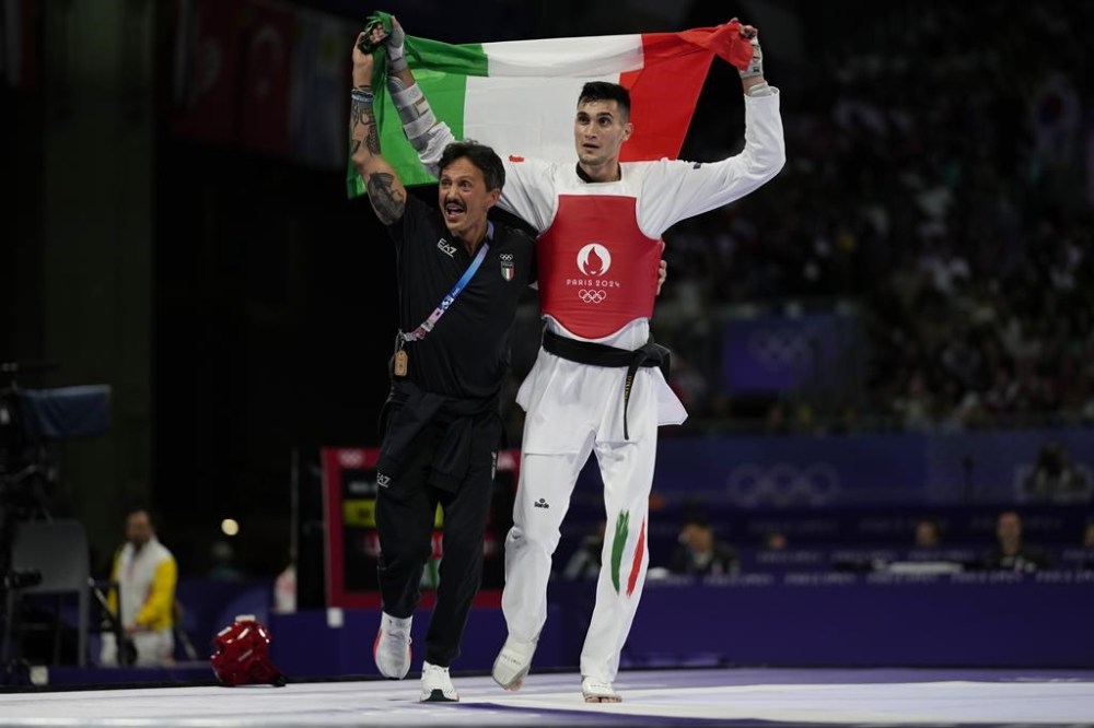 Italy's Simone Alessio celebrates with his coach after winning the men's 80kg Taekwondo bronze final match against United States' Cj Nickolas during the 2024 Summer Olympics, at the Grand Palais, Friday, Aug. 9, 2024, in Paris, France. (AP Photo/Andrew Medichini)