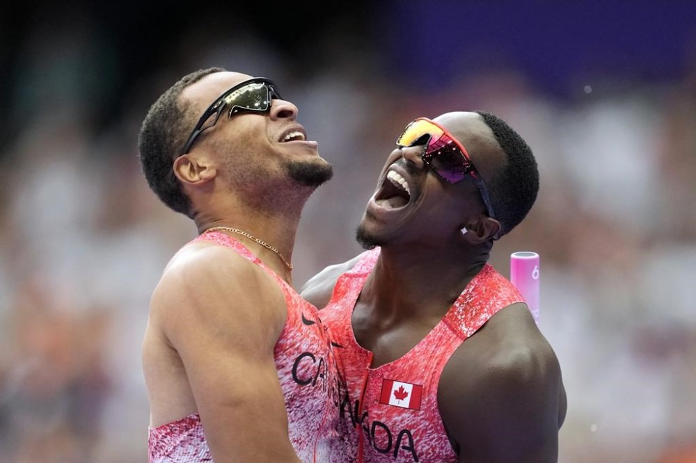 Aaron Brown, right, and Andre de Grasse, of Canada, celebrate after winning the gold medal in the men's 4 x 100 meters relay final at the 2024 Summer Olympics, Friday, Aug. 9, 2024, in Saint-Denis, France. Canada's men's 4x100-metre relay team claimed Olympic gold on Friday night at Stade de France in a stellar performance from Lane 9. With Andre De Grasse running the anchor leg, the Canadians posted a winning time of 37.50 seconds. (AP Photo/Ashley Landis)