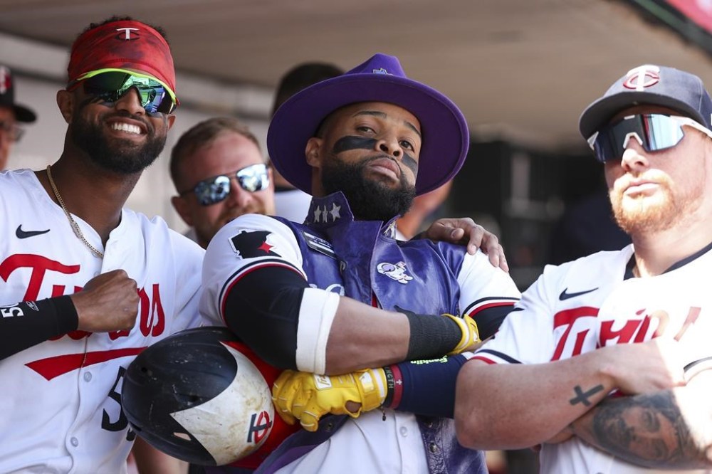 Minnesota Twins' Carlos Santana, center, celebrates his solo home run with teammates Willi Castro, left, and Christian Vázquez, right, in the dugout during the second inning of the first game of a baseball doubleheader against the Cleveland Guardians, Friday, Aug. 9, 2024, in Minneapolis. (AP Photo/Matt Krohn)