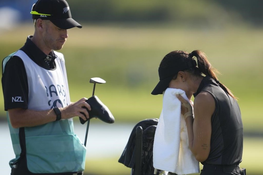 Lydia Ko, of New Zealand, cries and wipes her tears away with a towel as she celebrates on the 18th green after winning the gold medal after the final round of the women's golf event at the 2024 Summer Olympics, Saturday, Aug. 10, 2024, at Le Golf National, in Saint-Quentin-en-Yvelines, France. (AP Photo/Matt York)