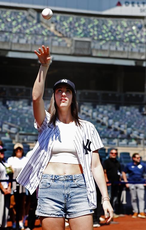WNBA basketball player Caitlin Clark throws a baseball before a baseball double game between the New York Yankees and the Texas Rangers, Saturday, Aug. 10, 2024 in New York. (AP Photo/Noah K. Murray)