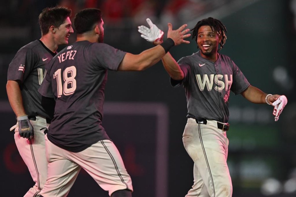 Washington Nationals' Jacob Young, left, and Juan Yepez (18) congratulate teammate Jose Tena, right, after Tena drove in the winning run during the 10th inning of a baseball game against the Los Angeles Angels, Saturday, Aug. 10, 2024, in Washington. (AP Photo/John McDonnell)