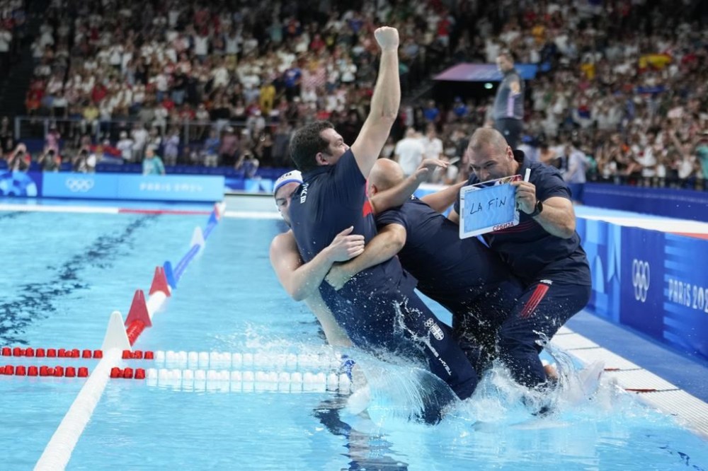 Serbia's head coach Uros Stevanovic is push into the pool as they celebrate winning the men's water polo gold medal match against Croatia, at the 2024 Summer Olympics, Sunday, Aug. 11, 2024, in Paris, France. (AP Photo/Luca Bruno)