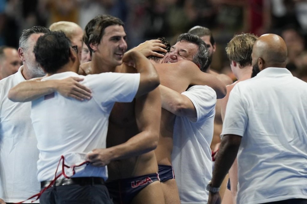 United States' head coach Dejan Udovicic, center, celebrates with players after winning the men's water polo bronze medal match against Hungary, at the 2024 Summer Olympics, Sunday, Aug. 11, 2024, in Paris, France. (AP Photo/Luca Bruno)