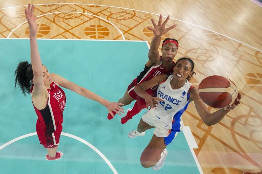 Marieme Badiane, right, (22), of France, shoots for a basket as United States' Breanna Stewart, left, (10) and United States' A'ja Wilson (9) attempt to block during a women's gold medal basketball game between the United States and France at Bercy Arena at the 2024 Summer Olympics, Sunday, Aug. 11, 2024, in Paris, France. (AP Photo/Mark J. Terrill, Pool)