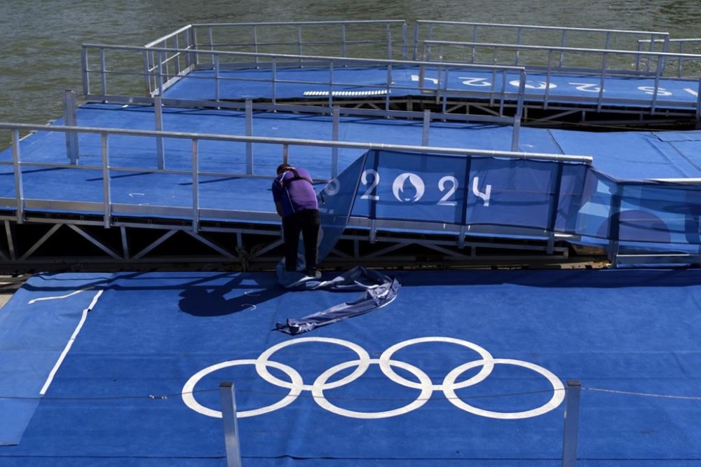A worker takes down Olympic signage from the pontoon used for swim events along the Seine River ahead of tomorrow's closing ceremony at the 2024 Summer Olympics, Saturday, Aug. 10, 2024, in Paris, France. (AP Photo/David Goldman)