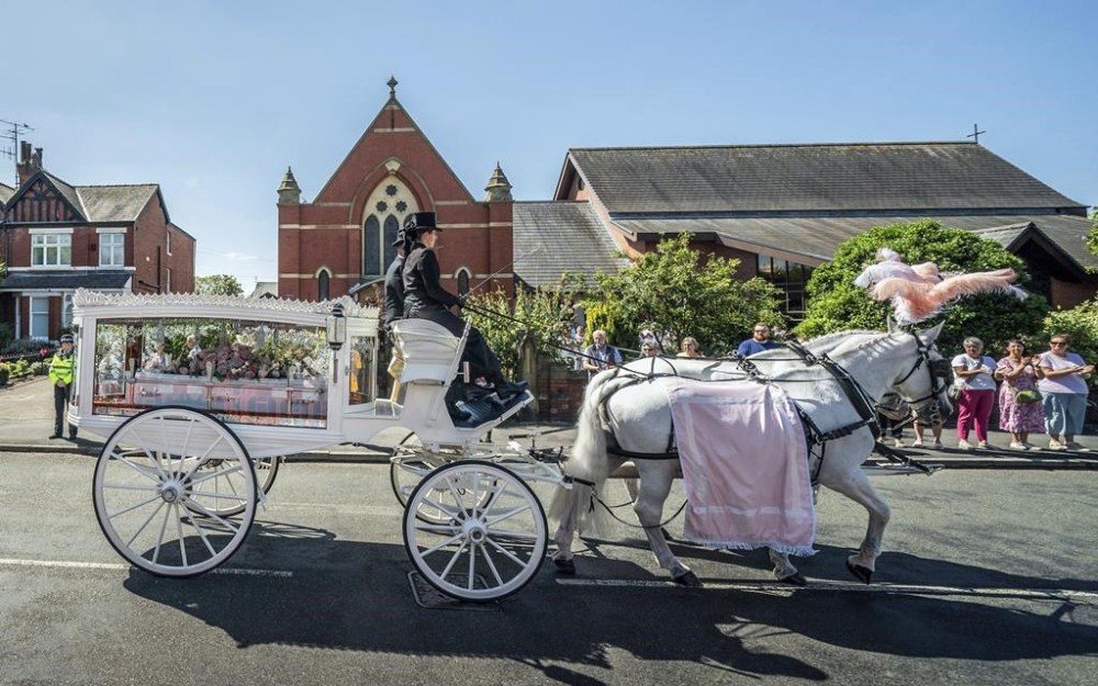 The horse-drawn carriage carrying the coffin of stabbing victim Alice da Silva Aguiar arrives for her funeral at St Patrick's Church, Southport, England, Sunday Aug. 11, 2024. (Danny Lawson/PA via AP)