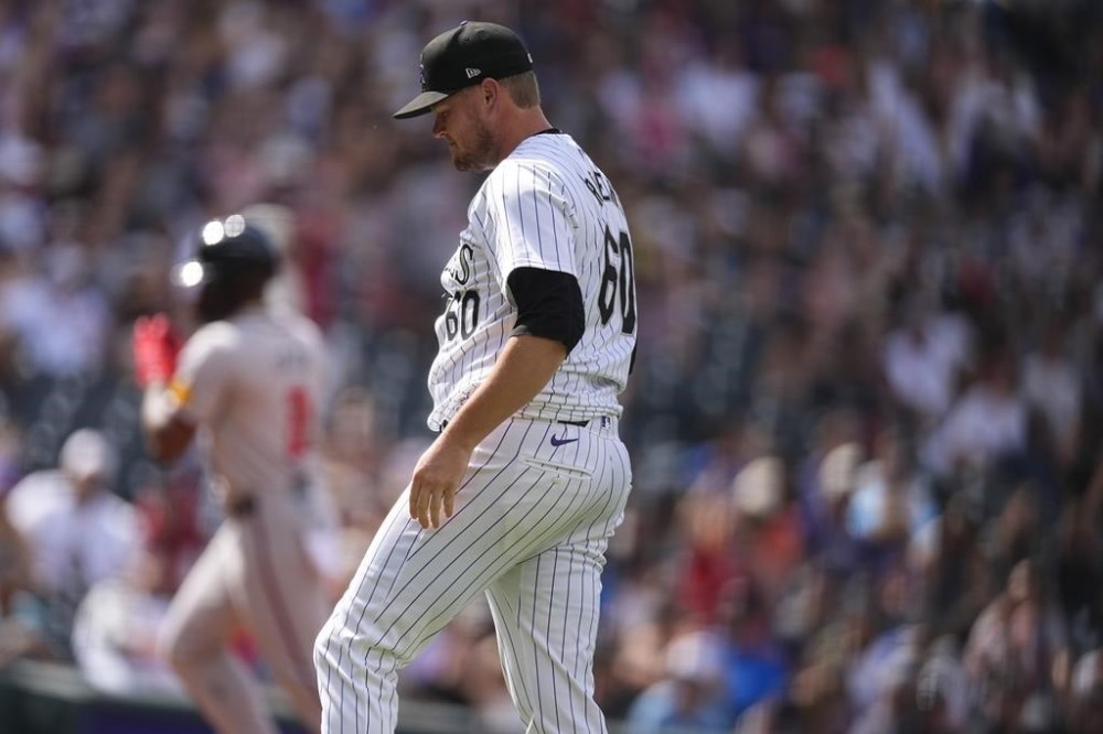 Colorado Rockies relief pitcher Josh Rogers, front, reacts after giving up a solo home run to Atlanta Braves' Jorge Soler, back, in the eighth inning of a baseball game Sunday, Aug. 11, 2024, in Denver. (AP Photo/David Zalubowski)