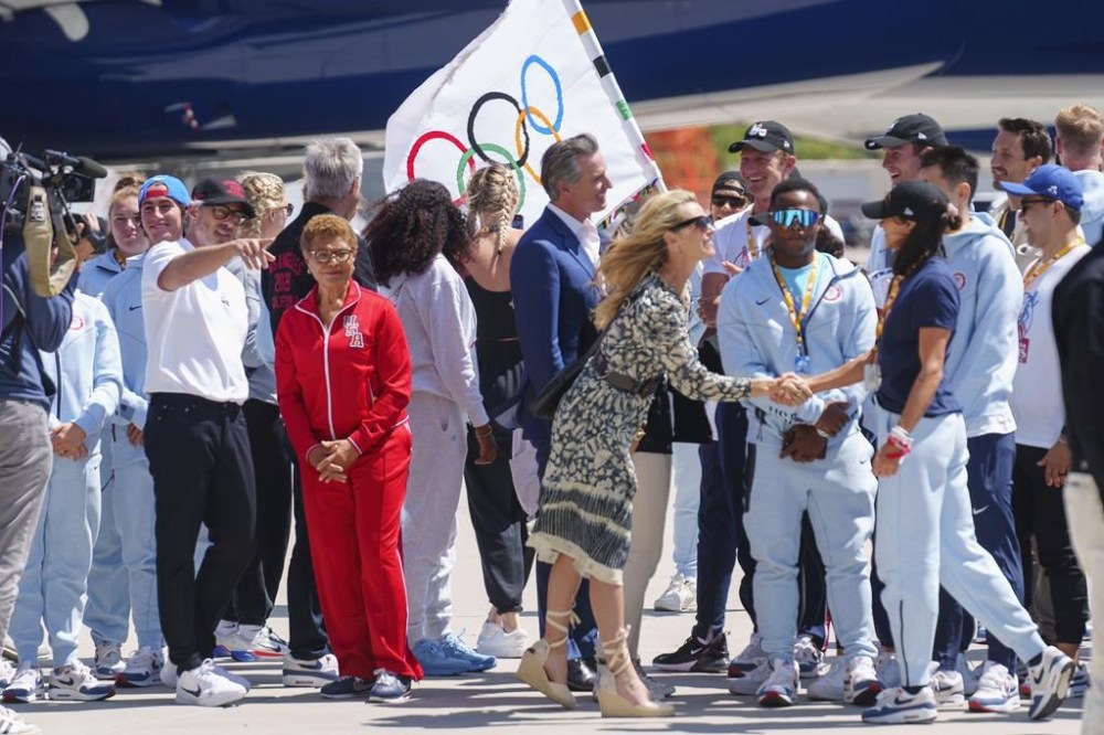 California Gov. Gavin Newsom, and his wife, first partner Jennifer Siebel-Newsom, front, welcome Team USA Olympians returning with the official Olympic flag at Los Angeles International Airport on Monday, Aug. 12, 2024. LA28 chairman Casey Wasserman, in on far left, with Los Angeles Mayor Karen Bass. (AP Photo/Damian Dovarganes)
