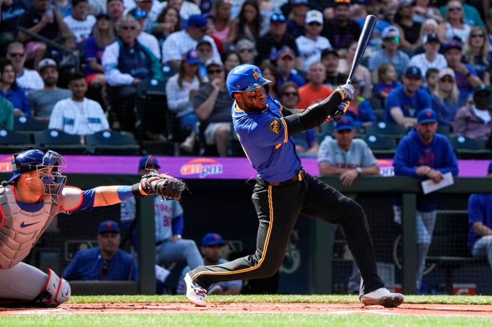 Seattle Mariners' Victor Robles, right, hits the ball for a foul during the first inning of a game against the New York Mets, Sunday, Aug. 11, 2024, in Seattle. (AP Photo/Liv Lyons)