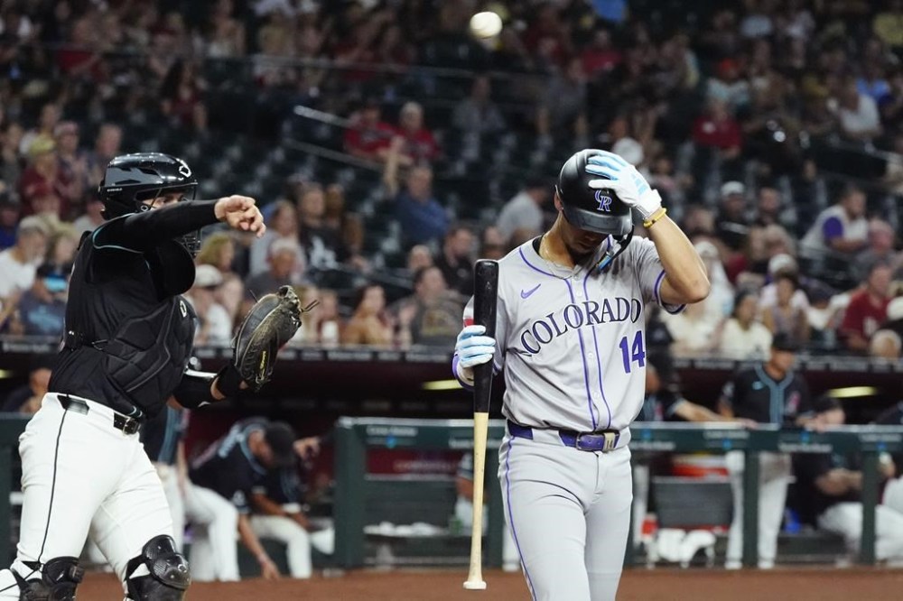 Colorado Rockies shortstop Ezequiel Tovar (14) walks back to the dugout after striking out as Arizona Diamondbacks catcher Adrian Del Castillo, left, throws the ball to the first baseman during the third inning of a baseball game, Monday, Aug. 12, 2024, in Phoenix. (AP Photo/Ross D. Franklin)