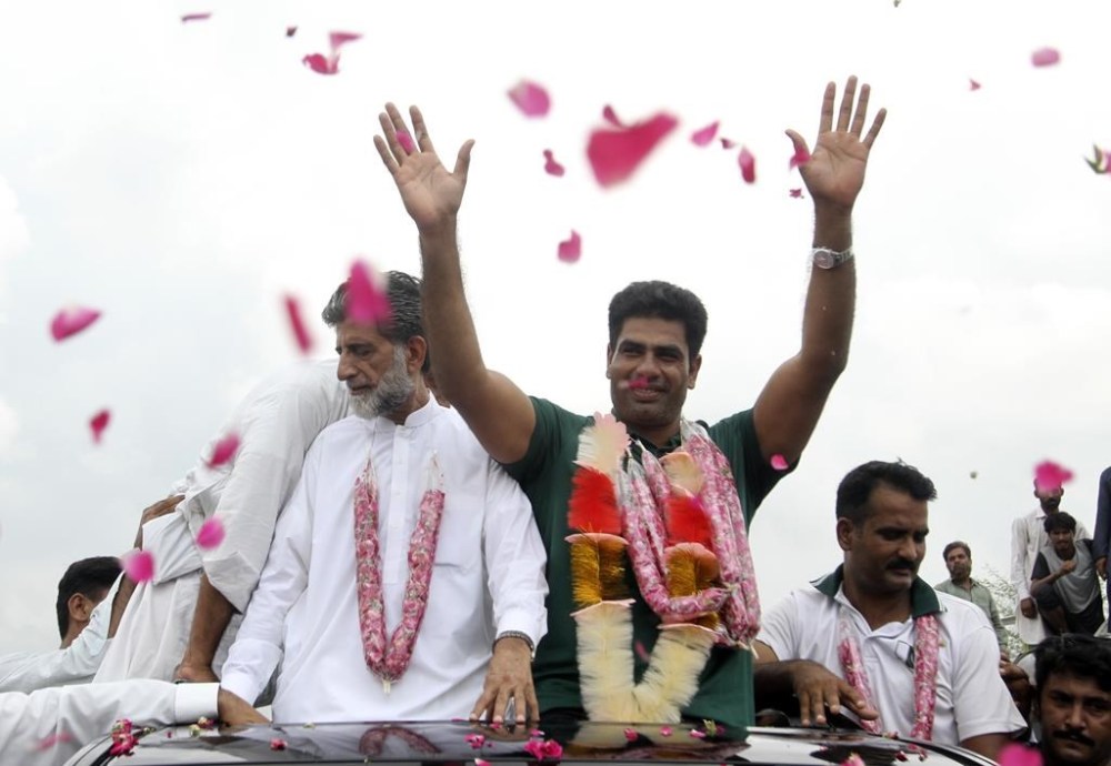 Men's javelin gold medalist, Arshad Nadeem of Pakistan, centre, waves to people outside his village in Mian Channu, Khanewal district, of Pakistan, Sunday, Aug. 11, 2024. (AP Photo/Asim Tanveer)