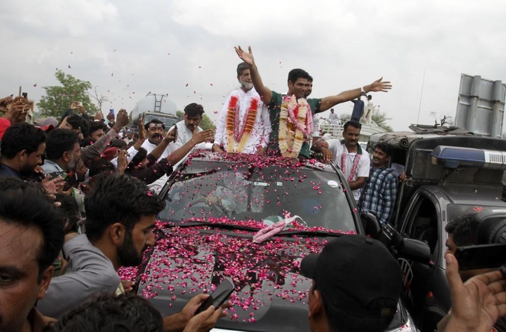 Men's javelin gold medalist, Arshad Nadeem of Pakistan, centre, waves to people outside his village in Mian Channu, Khanewal district, of Pakistan, Sunday, Aug. 11, 2024. (AP Photo/Asim Tanveer)