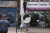 People remove a new artwork by Banksy, depicting a howling wolf painted on a satellite dish that was placed on a shop roof in Peckham, south London, Thursday Aug. 8, 2024. (Jordan Pettitt/PA via AP)