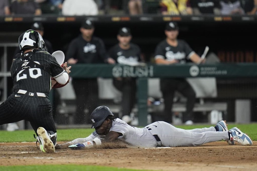 New York Yankees' Jazz Chisholm Jr., right, dives by Chicago White Sox catcher Korey Lee, left, to score on a single by Anthony Volpe during the fifth inning of a baseball game Monday, Aug. 12, 2024, in Chicago. (AP Photo/Erin Hooley)