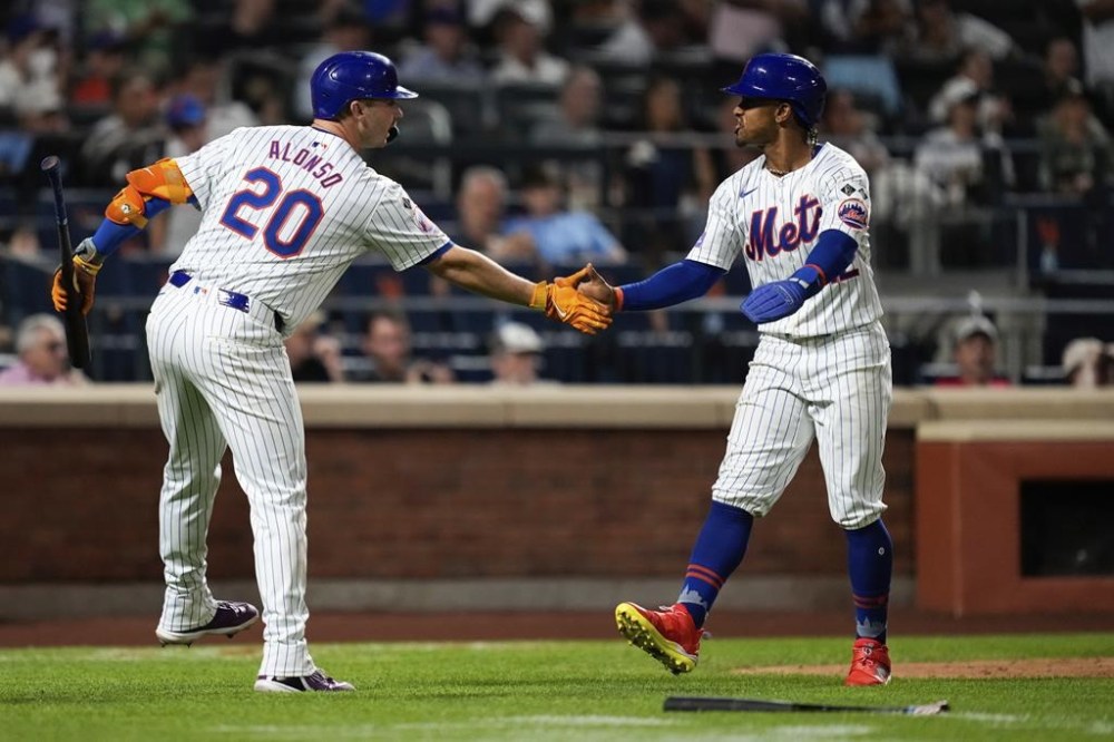 New York Mets' Francisco Lindor, right, low fives Pete Alonso (20) after scoring on Jesse Winker's line drive during the fifth inning of a baseball game against the Oakland Athletics, Tuesday, Aug. 13, 2024, in New York. (AP Photo/Julia Nikhinson)