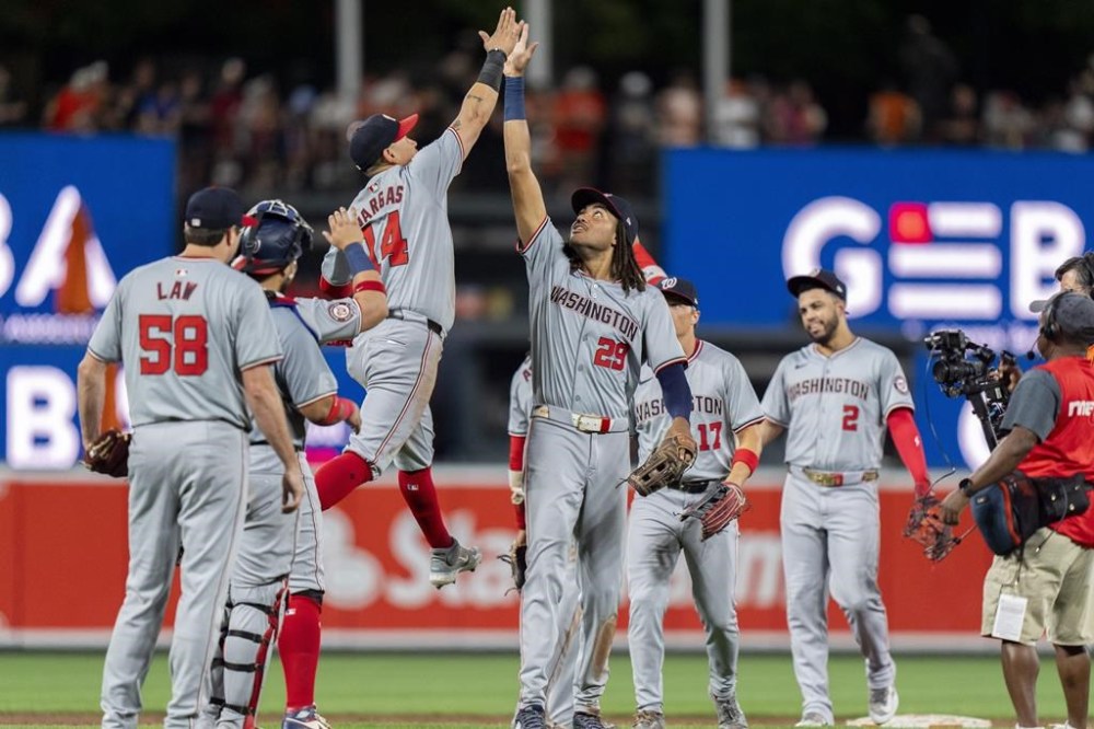 Washington Nationals third baseman Ildemaro Vargas (14) and Washington Nationals left fielder James Wood (29) celebrate their team's win over the Baltimore Orioles after a baseball game Tuesday, Aug. 13, 2024, in Baltimore. (AP Photo/Stephanie Scarbrough)