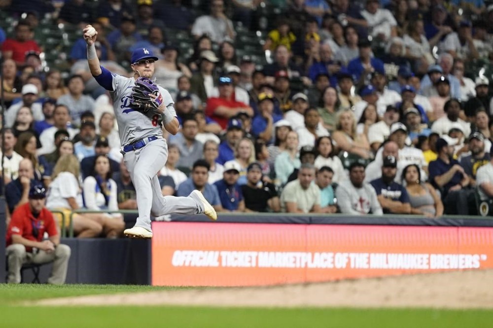 Los Angeles Dodgers' Enrique Hernández jumps after fielding a ground ball hit by Milwaukee Brewers' Joey Ortiz during the seventh inning of a baseball game Tuesday, Aug. 13, 2024, in Milwaukee. Ortiz was safe on the play. (AP Photo/Aaron Gash)