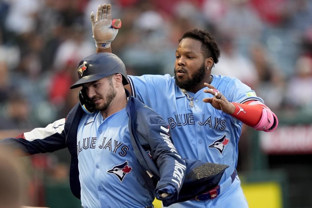 Toronto Blue Jays' Spencer Horwitz, left, is given a ceremonial jacket by Vladimir Guerrero Jr. after hitting a solo-home run during the third inning of a baseball game against the Los Angeles Angels, Tuesday, Aug. 13, 2024, in Anaheim, Calif. (AP Photo/Ryan Sun)
