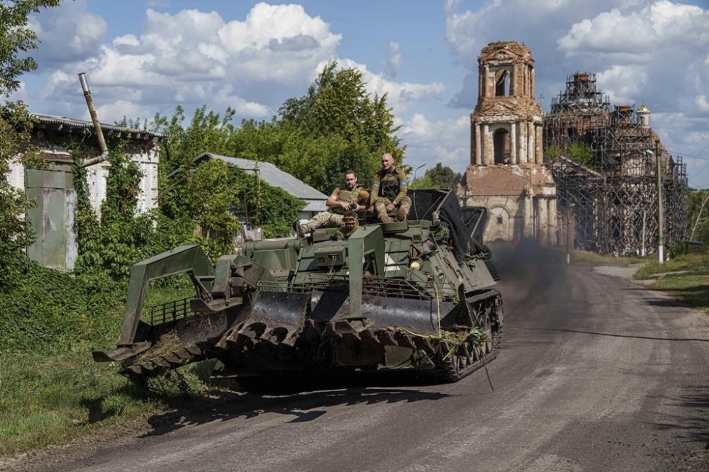 Ukrainian servicemen ride atop on armoured vehicle at the Russian-Ukrainian border in Sumy region, Ukraine, Wednesday, Aug. 14, 2024. (AP Photo/Evgeniy Maloletka)
