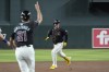 Arizona Diamondbacks' Joc Pederson, right, laughs as he runs to third base as Diamondbacks third base coach Tony Perezchica (21) waves Pederson home after a double and a two-base error during the first inning of a baseball game against the Colorado Rockies, Wednesday, Aug. 14, 2024, in Phoenix. (AP Photo/Ross D. Franklin)
