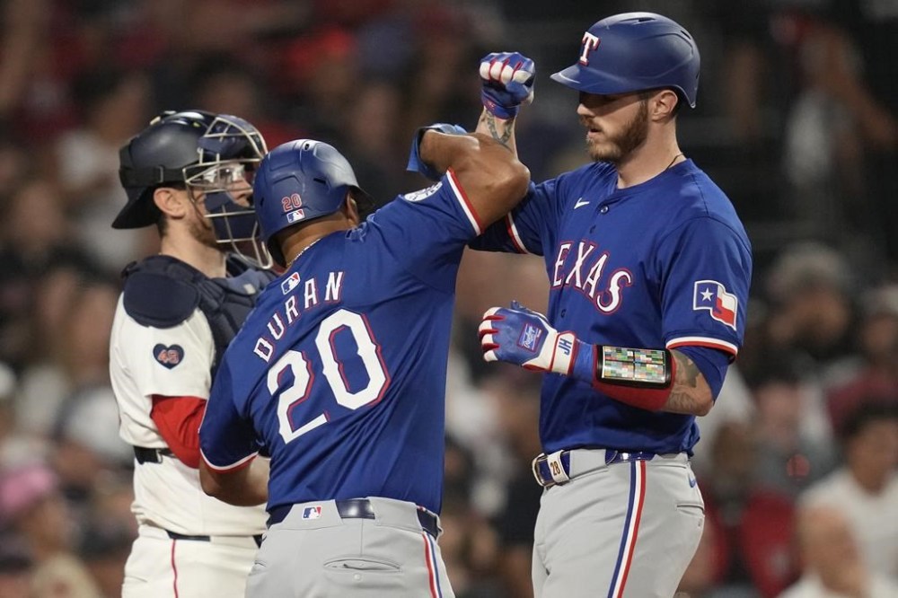 Texas Rangers' Jonah Heim, right, is congratulated by Ezequiel Duran (20) after his two-run home in the 10th inning of a baseball game at Fenway Park, Wednesday, Aug. 14, 2024, in Boston. At left is Boston Red Sox catcher Danny Jansen. (AP Photo/Charles Krupa)