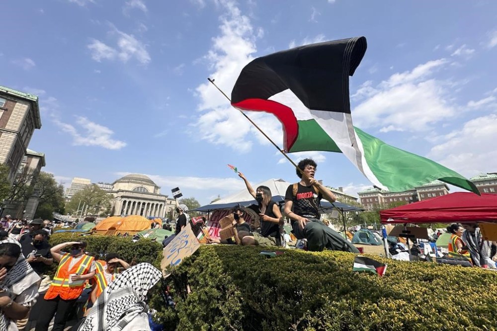 FILE - A demonstrator waves a flag on the Columbia University campus at a pro-Palestinian protest encampment, in New York, April 29, 2024. (AP Photo/Ted Shaffrey, File)