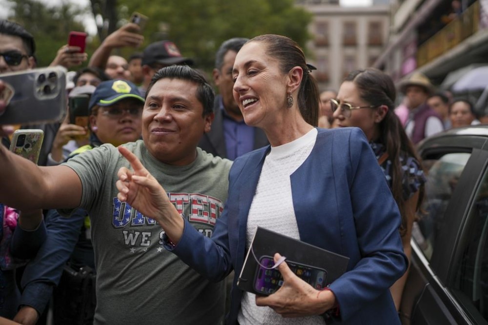 Mexican President-elect Claudia Sheinbaum poses for photos with protesters as she arrives to the Museum of Mexico City for a meeting, Monday, July 29, 2024. The protesters, from Tlahuac, say their lands were expropriated years ago by a previous state government. (AP Photo/Marco Ugarte)