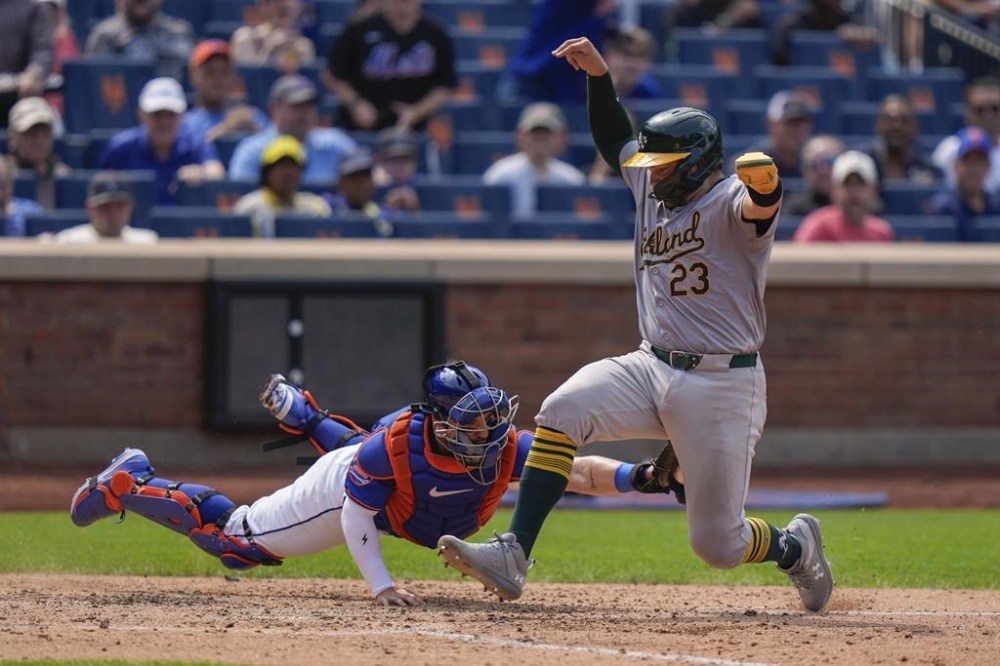 New York Mets catcher Luis Torrens reaches for Oakland Athletics' Shea Langeliers (23) at home plate during the fourth inning of a baseball game, Thursday, Aug. 15, 2024, in New York. After review, Langeliers was called out at home plate. (AP Photo/Frank Franklin II)