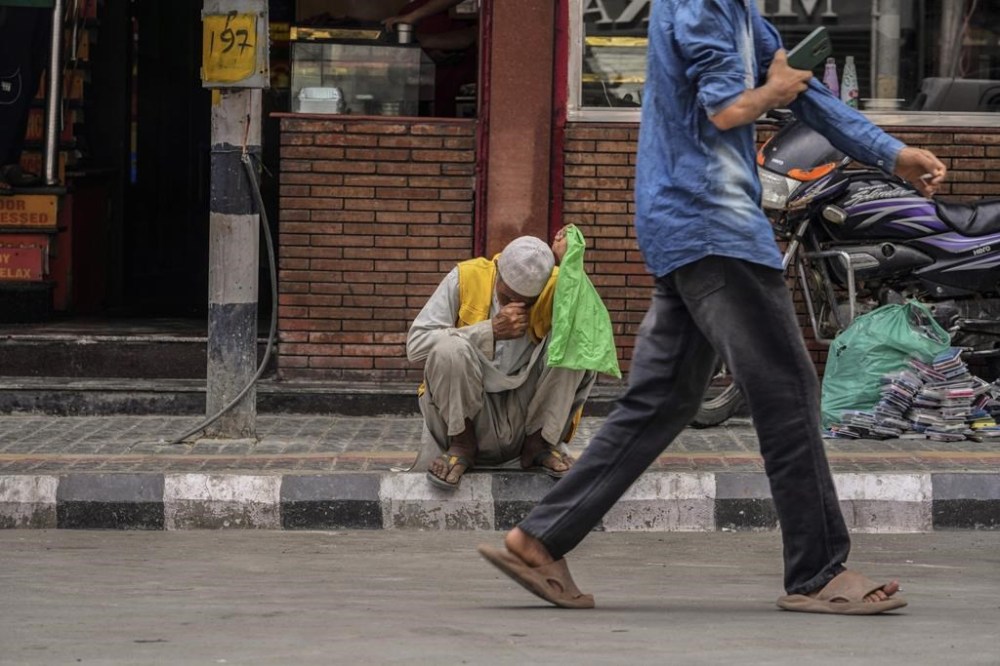 An elderly man rests on a sidewalk at a busy market in Srinagar, Indian controlled Kashmir, Friday, Aug.16, 2024. (AP Photo/Mukhtar Khan)
