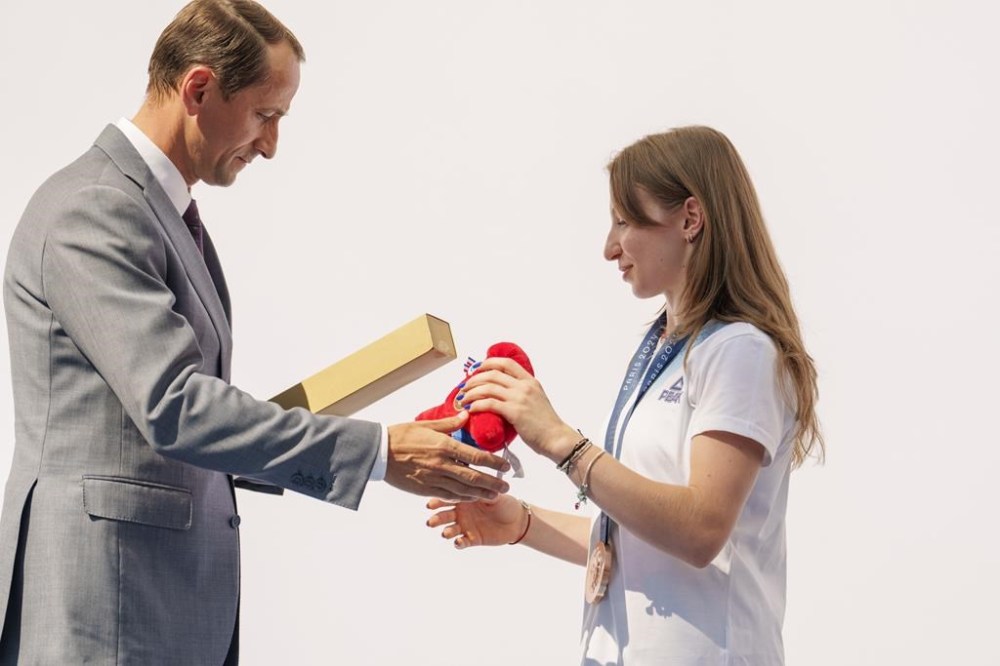 Mihai Covaliu, President of the Romanian Olympic and Sports Committee offers the Olympic games mascot to Romanian gymnast Ana Barbosu after she received the bronze medal for her women's artistic gymnastics individual floor performance at the Paris 2024 Olympics, during a ceremony, in Bucharest, Romania, Friday, Aug. 16, 2024. American gymnast Jordan Chiles called an arbitration panel's decision that dropped her out of the bronze medal position in the floor exercise at the Paris Olympics