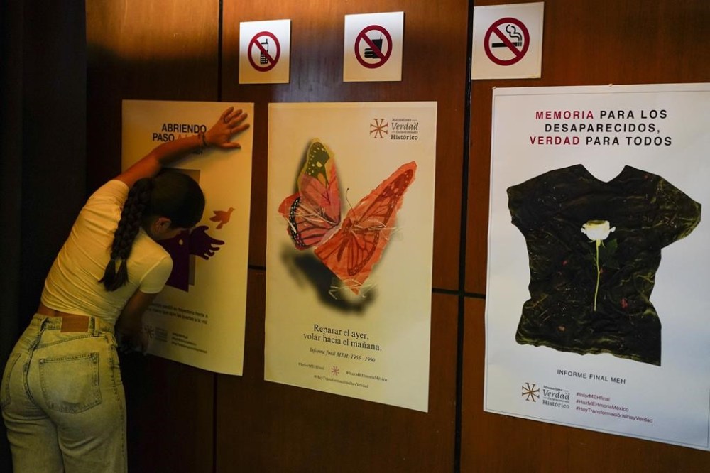 Posters about missing people are placed on a wall for the presentation of a report about the country’s 1965-1990 “dirty war” by Mexico's governmental Truth Commission in Mexico City, Friday, Aug. 16, 2024. The poster at right reads in Spanish