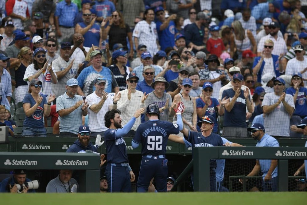 Chicago Cubs' Pete Crow-Armstrong (52) celebrates with manager Craig Counsell, center right, and teammate Dansby Swanson, left, at the dugout after hitting a solo home run during the fifth inning of a baseball game against the Toronto Blue Jays in Chicago, Friday, Aug. 16, 2024. (AP Photo/Paul Beaty)
