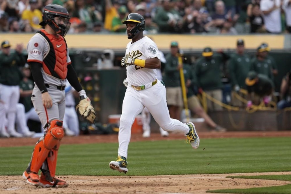 Oakland Athletics' Miguel Andujar, center, scores on Seth Brown's single during the sixth inning of a baseball game against the San Francisco Giants, Saturday, Aug. 17, 2024, in Oakland, Calif. (AP Photo/Godofredo A. Vásquez)