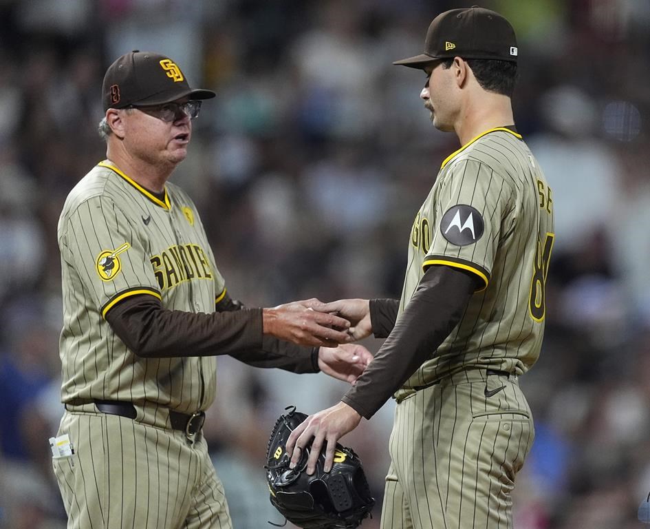 San Diego Padres manager Mike Shildt, left, takes the ball from starting pitcher Dylan Cease who is pulled from the mound after giving up a two-run home run to Colorado Rockies' Michael Toglia in the sixth inning of a baseball game Saturday, Aug. 17, 2024, in Denver. (AP Photo/David Zalubowski)